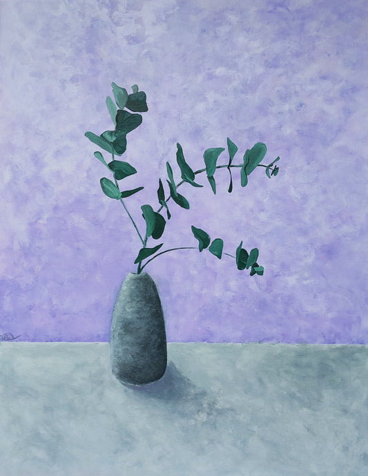 A textured concrete vase containing 3 stems of green foliage on a light grey surface with a lilac background wall. 