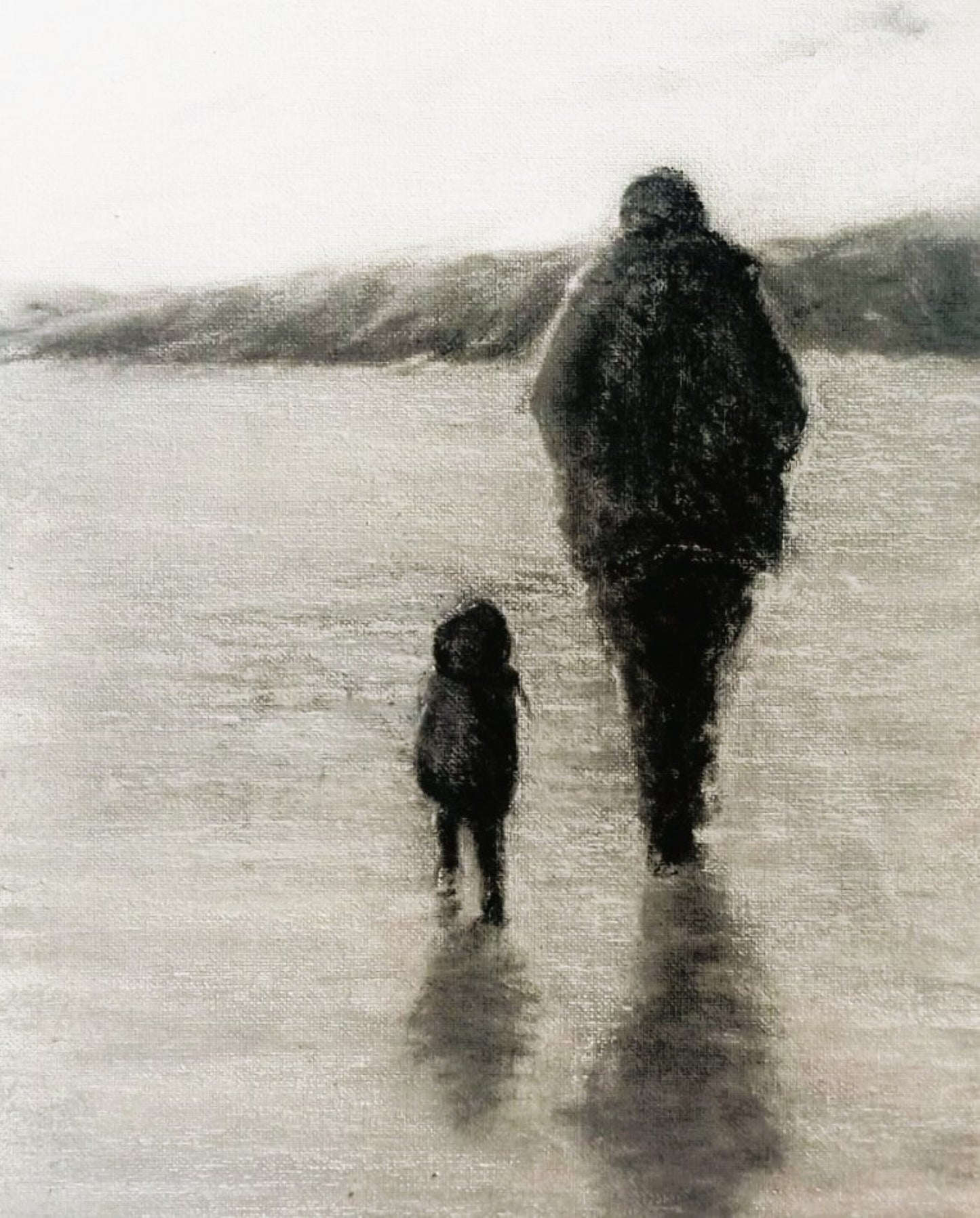 Adult and child in raincoats on a wet beach walking away with shadow on floor in black and white